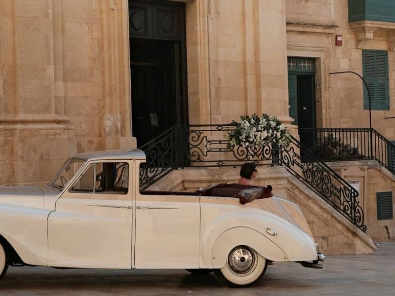 Vintage white wedding car at an elegant stone entrance